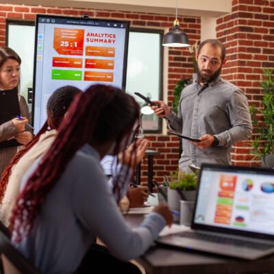 Business team analyzing marketing strategies with digital charts on led monitor. Professionals in office discussing financial analysis, utilizing modern technology for online data and information.